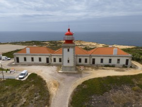 Lighthouse and long building along the coast, with view to the sea and cloudy sky, aerial view,