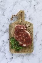 Raw pork steak, pork neck, on a chopping board, marble table, top view, with spices and coriander,