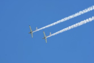 Stunt aerobatic plane performing stunts in blue sky with smoke trail. Concept of teamwork,