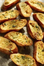 Baguette toasts, baked in the oven, with garlic butter and herbs, homemade, on a platter, top view