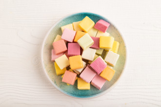 Various fruit jelly chewing candies on plate on white wooden background. apple, banana, tangerine,