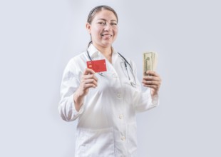 Beautiful and smiling female doctor holding money and credit cards. Happy female doctor holding