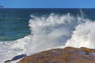 Sea water splashing after a wave crashes hard against the rocks on Ipanema beach in Rio de Janeiro,