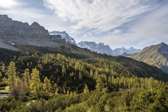 Mountain panorama with steep rocky peaks, yellow-coloured larches in autumn, hike to the summit of