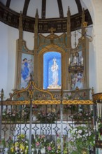 Artfully decorated church altar with flowers, statue of the Virgin Mary and golden ornaments,