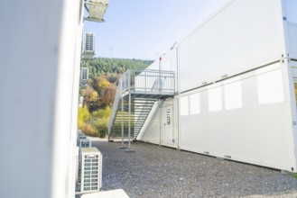 Side view of a container building with air conditioning and metal staircase, refugee accommodation