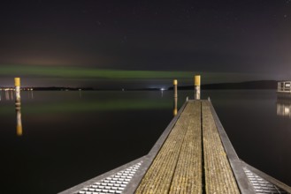 Northern lights (aurora borealis) shine on a starry night over Lake Plau, Ganzlin,