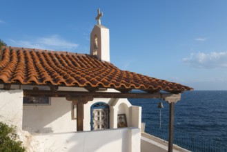 Chapel building with red bricks by the sea under a blue sky, radiates peace, Church of Agios