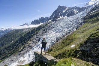 Mountaineer standing on a rock, mountain landscape with glacier Glacier des Bossons and summit of