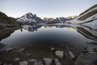 Tourist at a mountain lake in the morning, mountain landscape at sunrise, water reflection in Lac