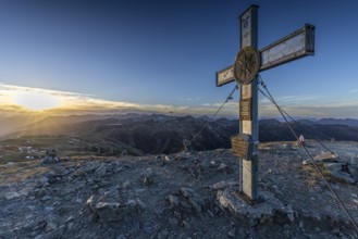 Summit cross on the Wildkogel at sunset offers a breathtaking view of the mountain landscape,