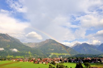 View over Oberstdorf with rainbow, behind it the Schattenberg with Schattenbergschanze, Oberallgäu,