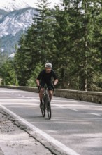 Road bike rider in spring in the Allgäu against the picturesque backdrop of the Alps, Bavaria,