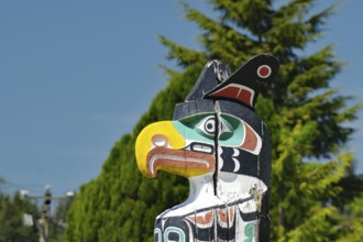 A detailed totem pole with a stylised bird's head outdoors, totems at an old cemetery in Alert Bay,