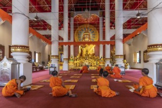 Monks and novices praying in the Buddhist temple Wat Phra Singh, Chiang Mai, Thailand, Asia