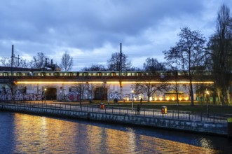 S-Bahn train runs along the Spree at Monbijou Park, walkers at blue hour, Berlin, 02.01.2025