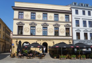 Historic facades with art and street cafés under a blue sky, Klonowica tenement house, Old Town,