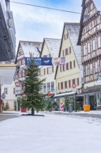 Snow-covered street in a town with traditional half-timbered architecture and decorated Christmas