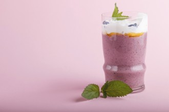 Smoothie with honeysuckle, linen and chia in a glass on pink pastel background. side view, close