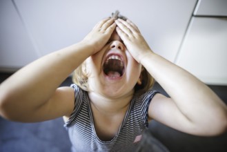 Symbolic photo on the subject of tantrums in children (staged scene) . A little girl holds her