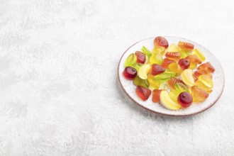 Various fruit jelly candies on plate on gray concrete background. side view, copy space