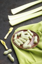 Jelly celery candies on black concrete background and green linen textile. close up, side view