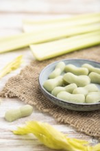 Jelly celery candies on white wooden background and linen textile. close up, side view, selective