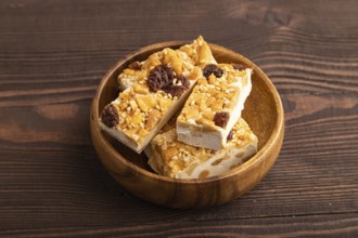 Traditional candy nougat with nuts and sesame on brown wooden background. side view, close up