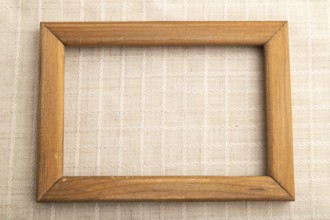 Wooden frame on smooth white linen tissue. Top view, flat lay, natural textile background and