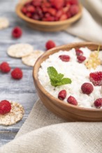 Rice flakes porridge with milk and strawberry in wooden bowl on gray wooden background and linen