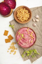 Hummus with beet and microgreen basil sprouts in wooden bowl on a white wooden background and linen