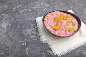 Hummus with beet and microgreen basil sprouts in ceramic bowl on a black concrete background and