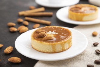 Sweet tartlets with almonds and caramel cream with cup of coffee on a black concrete background and