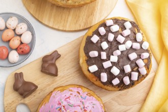 Homemade glazed and decorated easter pies with chocolate eggs and rabbits on a white concrete