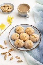 Almond cookies and a cup of coffee on a white concrete background and blue linen textile. Side