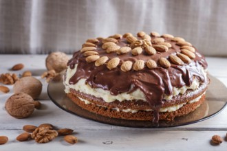 Homemade chocolate cake with milk cream and almonds on white wooden background. close up