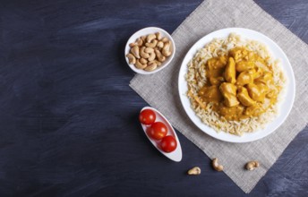 Rice with chicken curry sauce with cashew on black wooden background. top view, copy space