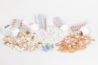 Various pills and tablets distributed around open medicine bottles