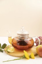 Red tea with herbs in glass teapot on white wooden background. Healthy drink concept. Top view,