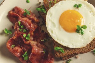 Breakfast, fried egg with bacon, micro-green, on a light background, no people, selective focus