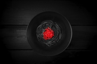 Black spaghetti with red caviar, pasta, on a black background, top view, no people