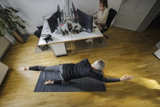 Symbolic photo on the subject of occupational health management. A woman exercises on a sports mat