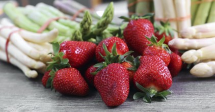 Green asparagus, white asparagus and fresh strawberries decorated on a rustic wooden table