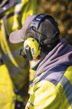 Profile view of a worker with safety helmet and hearing protection in dialogue, glass fibre