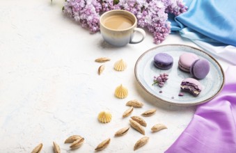 Purple macarons or macaroons cakes with cup of coffee on a white concrete background and