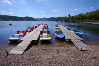 A picturesque scene with colourful pedal boats and wooden boats on a jetty in front of the