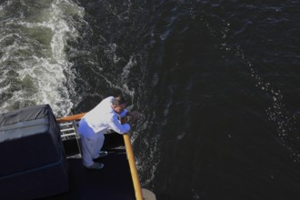 Man standing at the stern of a cruise ship looking into the water of the Nile, Egypt, Africa