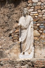 Statue of Augustus in front of a colourful stone wall, symbolising Roman history and ancient art,