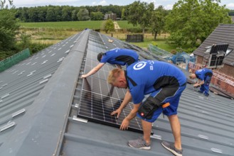 Installation of solar modules on the roof of a barn on a farm, over 240 photovoltaic modules are