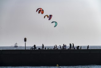 Kitesurfer off the coast of Scheveningen, walkers on the harbour pier, The Hague, Netherlands